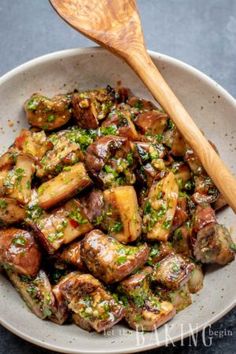 a white bowl filled with potatoes covered in sauce and garnished with parsley