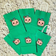 four green bags with pictures of pumpkins on them sitting on the floor in front of a pile of carpet