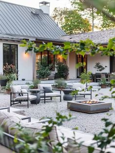 an outdoor living area with couches, chairs and fire pit in front of a house