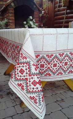 two white and red tablecloths sitting on top of a wooden bench next to a fire place