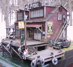 an old fashioned boat house with people on the deck and in the water next to it