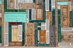 an assortment of wooden doors and shutters are stacked on top of each other in different colors