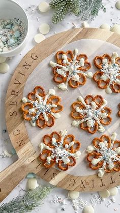 a wooden board topped with pretzels on top of a white table next to christmas decorations