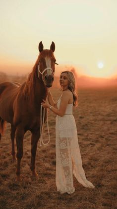 a woman standing next to a brown horse on top of a dry grass covered field