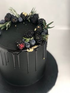 a black cake with berries and leaves on top