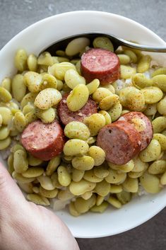 a white bowl filled with green beans and sausage