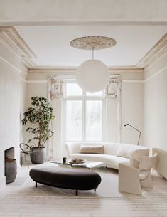 a living room with white furniture and a plant in the corner on top of the coffee table