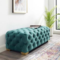 a living room with a large rug and a blue tufted bench in front of a window