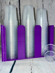 purple and white plastic cups are lined up in a row on a wooden table top