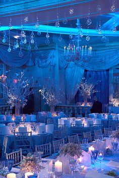 an image of a banquet room set up for a formal function with blue lighting and chandeliers