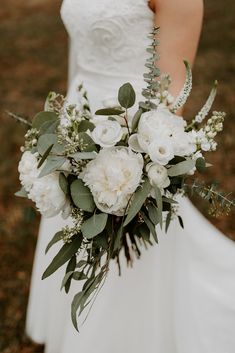 a bridal holding a bouquet of white flowers and greenery