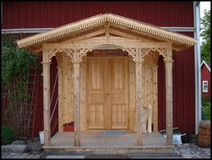 a wooden gazebo sitting in front of a red building