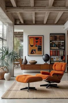 an orange chair and ottoman in a modern living room with large windows, bookshelves and artwork on the wall