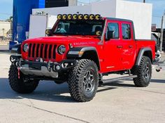 a red jeep parked in front of a gas station