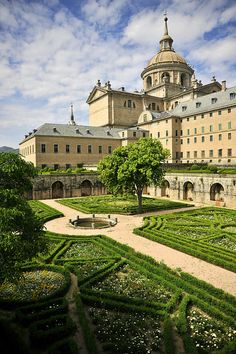 a large building with many hedges in front of it and a tree on the other side