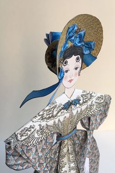 a paper doll wearing a blue hat and dress