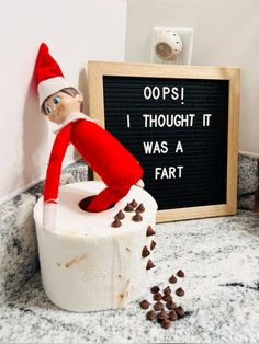 an elf is sitting on top of a toilet paper roll with chocolate chips scattered around it