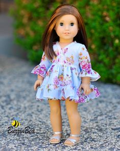 the doll is wearing a blue dress with pink flowers on it and has long brown hair