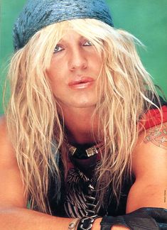 a man with long blonde hair and piercings on his arm posing for a photo