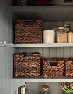 some baskets are sitting on shelves in the kitchen