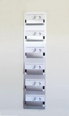 a white wall mounted shelf with four different types of papers on it's sides