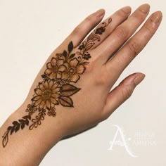 a woman's hand with a henna tattoo on her left wrist and flowers on it