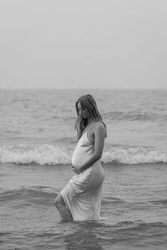 a pregnant woman is standing in the ocean