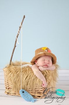 a baby sleeping in a basket next to a toy fish on a rope with a fishing hook