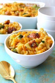 three bowls filled with pasta and broccoli on top of a blue tablecloth