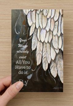 a hand holding up a card with an angel wings design on it, which reads your wings are already art all you have to do is