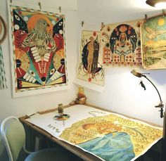 a room with paintings on the wall and a table in front of it that has a lamp next to it