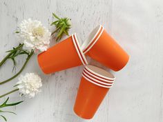 three orange cups sitting next to some white flowers