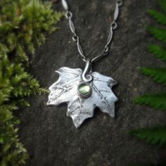 This elegant hand formed fine silver necklace is made from a real baby maple leaf that I have picked from the forest, and features a beautiful green 4mm peridot smooth cabochon. I have hand formed the bail to look like an organic part of the leaf. This necklace was very much inspired by my love of the forest and the elves of Tolkien. It has been oxidized to bring out the texture. The sterling silver chain can be made for you in various lengths, if you would like a different length than what is a Hand Forged Green Necklace In Nature-inspired Style, Handmade Sterling Silver Nature-inspired Necklace, Handmade Sterling Silver Leaf-shaped Necklace, Handmade Sterling Silver Leaf Necklace, Handmade Leaf-shaped Nature-inspired Jewelry, Nature-inspired Hand Forged Green Necklace, Nature-inspired Sterling Silver Leaf Necklace, Nature-inspired Leaf Shaped Sterling Silver Necklace, Nature-inspired Leaf Jewelry Gift