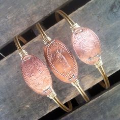 three pieces of copper sitting on top of a wooden bench