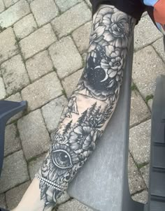 a person sitting on a motorcycle with a tattoo on their arm and leg, in front of a brick walkway