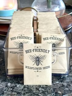 bee - friendly wildflower seed packets are stacked in a clear container on the counter