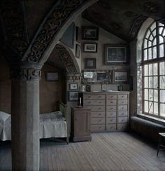 an old fashioned bedroom with wooden floors and arched windows, along with pictures on the wall