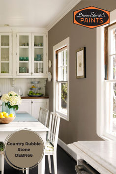 a kitchen with white cabinets and a table in front of the counter top that has a bowl of fruit on it