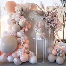 the balloon arch is decorated with pink and white balloons, flowers, and greenery