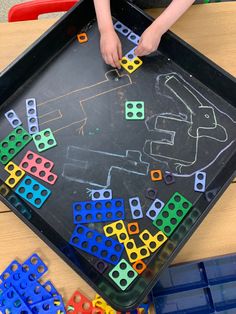 a child is playing with colored blocks on a tray