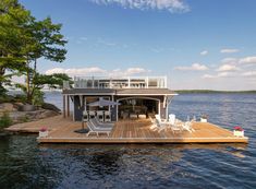 a boat dock with chairs and tables on it in the middle of water next to trees