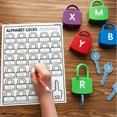 a child's hand holding a pencil and writing on alphabet locks