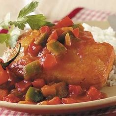 a white plate topped with meat covered in sauce and veggies next to rice