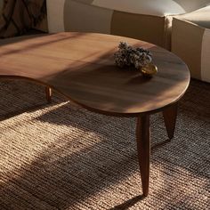 a wooden table sitting on top of a carpeted floor next to a white couch