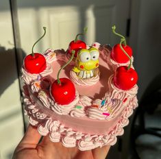 a pink cake with cherries on it and a spongebob figure in the middle