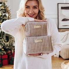 a woman is holding two velvet clutches in front of her face and smiling at the camera