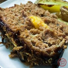 a white plate topped with meat and fruit next to a baked potato wedged on top of it