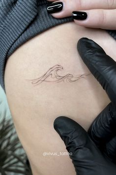 a woman's thigh with a wave tattoo on her left side ribcage