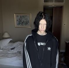 a young man with black hair wearing a adidas hoodie in a hotel room