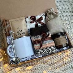 an open box with coffee, candles and other items in it sitting on a blanket